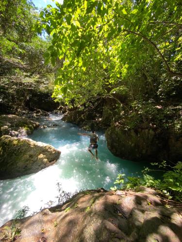 un hombre nadando en un río en un bosque en Hospedaje CatalinaSS no elegi nombre, en Liberia
