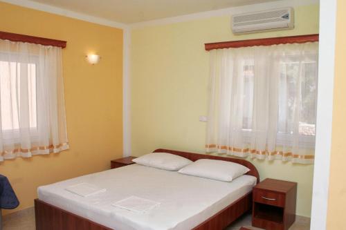 a small bedroom with a bed and two windows at Double Room Rogoznica 3097a in Rogoznica