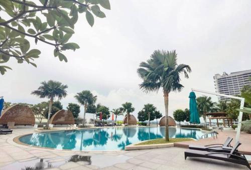 a pool at a resort with palm trees and chairs at 1719 Almas Suites Muji Studio100mbpsNetflix By STAY in Nusajaya