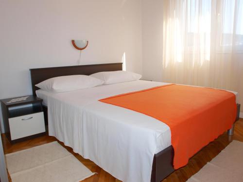 a bedroom with a large bed with an orange blanket at Apartments with a parking space Businci, Ciovo - 4667 in Trogir