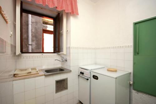a small kitchen with a sink and a refrigerator at Apartments by the sea Bol, Brac - 4657 in Bol
