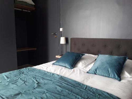 a large bed with two blue pillows on it at La Pomme d'Or in La Charité-sur-Loire