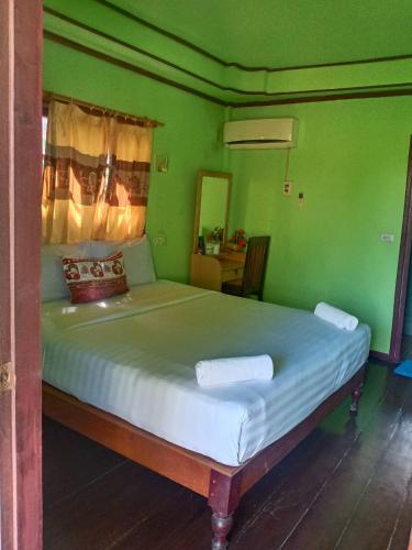 a bedroom with a large bed with green walls at Lao Long Riverside and Budget Garden Guesthouse in Ban Khon