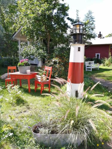 a lighthouse in a yard with a table and a bench at Guesthouse Lokinlaulu in Kotka
