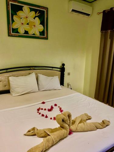 a teddy bear laying on a bed with red beads at Anugrah Bungallow in Gili Islands