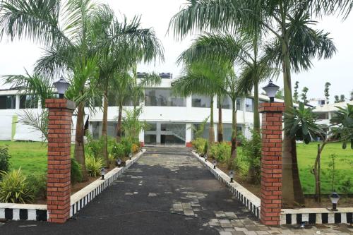 a walkway in front of a building with palm trees at RAJ RESORT & BANQUETS in Vapi