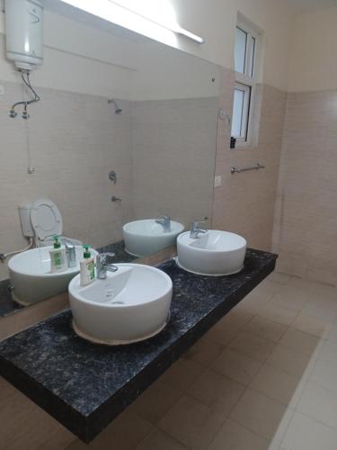 a bathroom with three sinks on a black counter at The Villa in Gurgaon