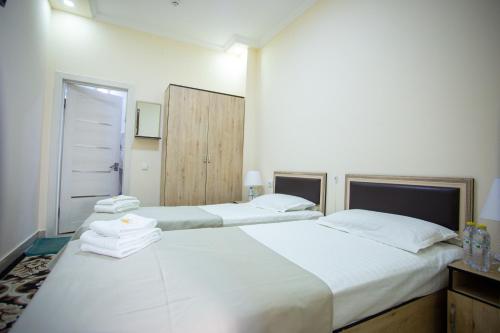 2 camas en una habitación con sábanas blancas y toallas en TINY ART HOUSE HOTEL near Airport of Samarkand en Samarcanda