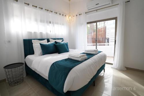 a bedroom with a large bed with blue and white pillows at YalaRent Afarsemon Apartments with pool - For Families & Couples in Eilat