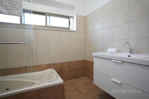 a white bathroom with a tub and a sink at YalaRent Afarsemon Apartments with pool - For Families & Couples in Eilat