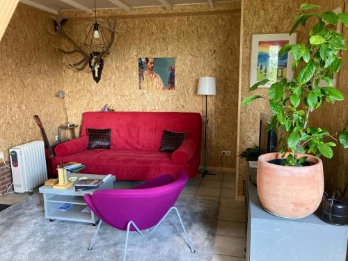 a living room with a red couch and purple chairs at Vakantiehuisje De Waddenuil 
