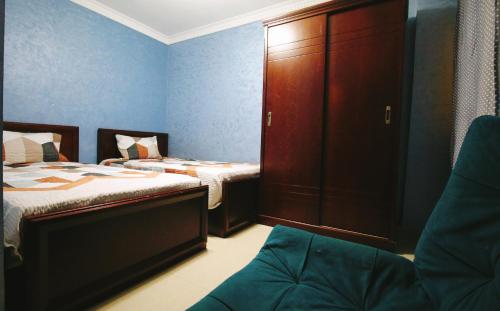 1 Schlafzimmer mit 2 Betten, einem Schrank und einem Stuhl in der Unterkunft Golden Charming 3-Bed Apartment in Cairo in Kairo