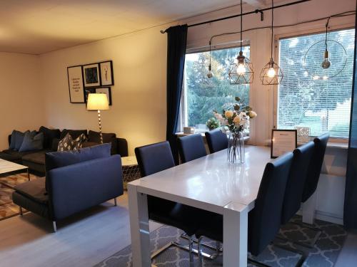 uma sala de jantar e sala de estar com uma mesa branca e cadeiras azuis em The White and Black House em Kalix