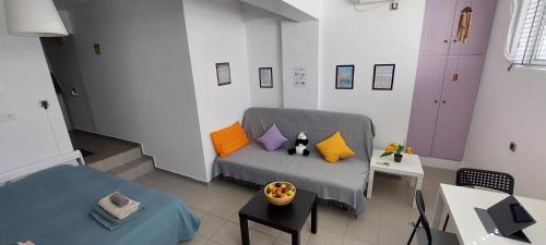 HoneyBee 1 - Sunny Studio in the center of Rafina في رافينا: غرفة معيشة مع أريكة رمادية مع وسائد ملونة