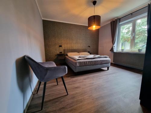 una camera con un letto e una sedia e una finestra di Ferienwohnung Ströbitzer Wiesen a Cottbus