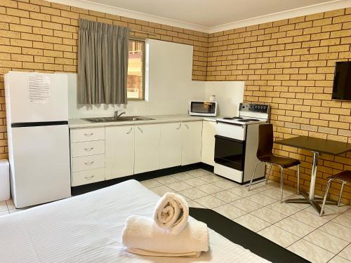 a kitchen with a white refrigerator and a table at Tallarook Motor Inn in Dubbo