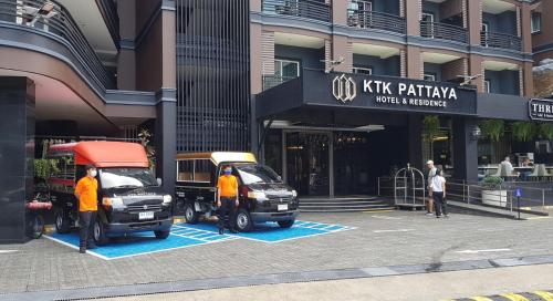 dwa samochody zaparkowane na parkingu przed budynkiem w obiekcie KTK Pattaya Hotel & Residence w mieście Pattaya Central