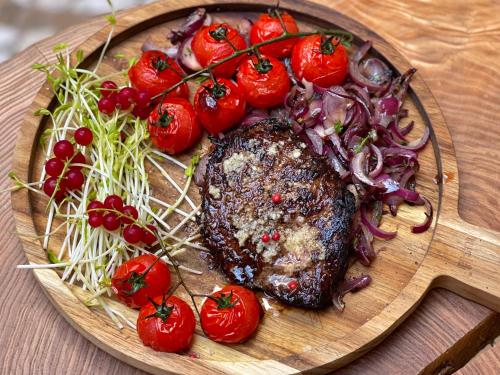 a plate with a steak and tomatoes on a table at Hotel Pan Tadeusz in Serock