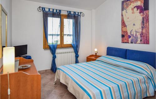 ein Schlafzimmer mit einem blauen Bett und einem Fenster in der Unterkunft Beautiful Home In Sabaudia With Jacuzzi in Sabaudia