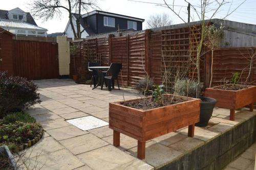 einen Garten mit einer Terrasse mit einem Tisch und einem Zaun in der Unterkunft Entire 3 bedroom house near Caerphilly station in Caerphilly
