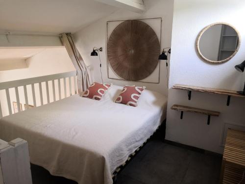 ラ・グランド・モットにあるAppartement du golfのベッドルーム1室(白いシーツと鏡付きのベッド1台付)