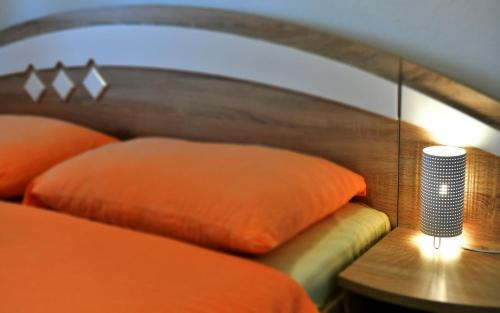 a bed with an orange pillow and a lamp on a table at Apartment Andreja in Seliste Dreznicko