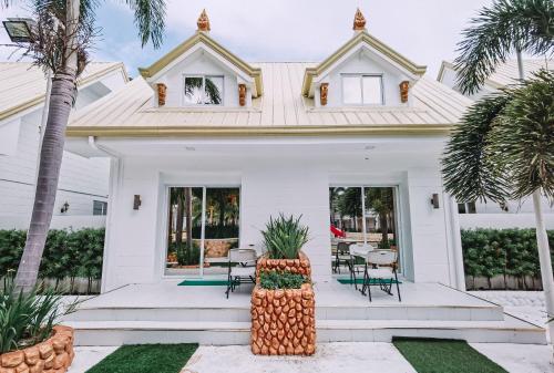 a white house with a table and chairs at Villa Excellance Beach and Wave Pool Resort in Postema