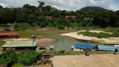 a river with a group of houses and a boat at Julies Hostel Taman Negara in Kuala Tahan