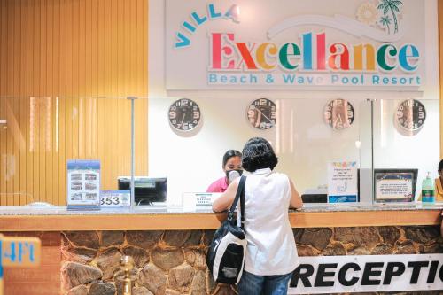 a woman standing in front of a beach and wave pool restaurant at Villa Excellance Beach and Wave Pool Resort in Postema