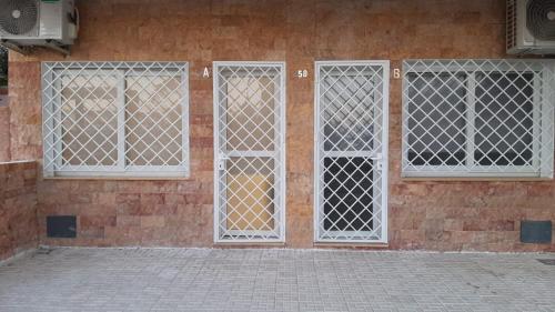 three windows on a brick building with white grilles at Apartamentos Montalvo Alessandri in Torremolinos