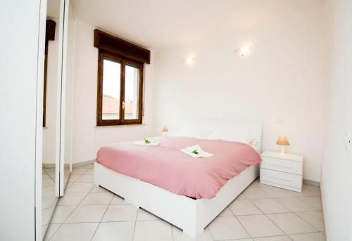 um quarto branco com uma cama rosa e uma janela em InnPisaRentals - Charme Pisa Toscana 2 em Pisa