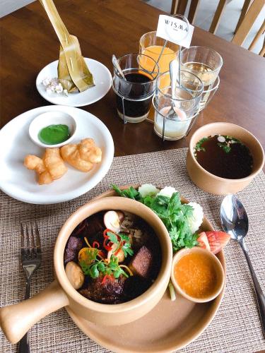 a table with a bowl of soup and a plate of food at Centara Life Wisma Hotel Ratchaburi in Ratchaburi