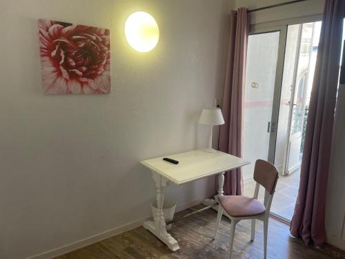 a white desk with a lamp and a chair in a room at Hotel Au Chapon Fin in Poitiers