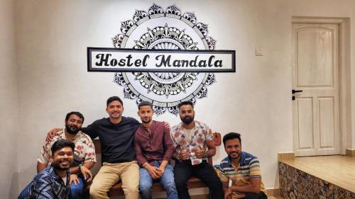 a group of men posing for a picture under a sign at Hostel Mandala in Anjuna