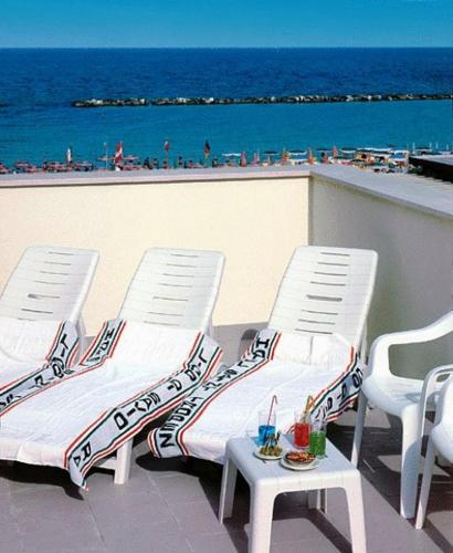 two chairs and a table on a balcony with the beach at Hotel Saint Tropez SPA & Restaurant in Lido di Savio