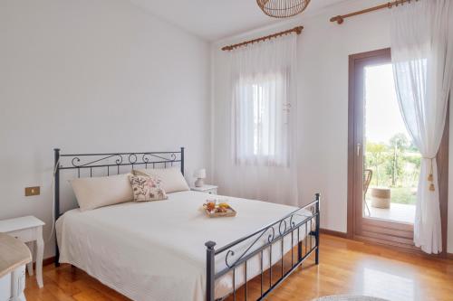- une chambre blanche avec un grand lit et une fenêtre dans l'établissement Le Vigne del Gallo, à Farra di Soligo