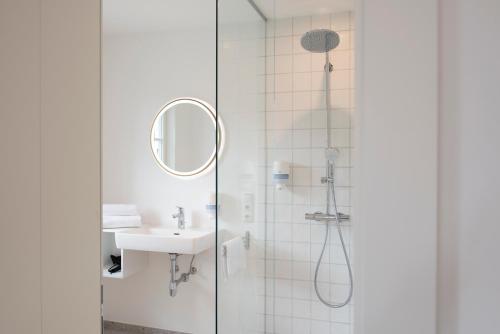 La salle de bains est pourvue d'une douche, d'un lavabo et d'un miroir. dans l'établissement Quartier 99, à Innsbruck