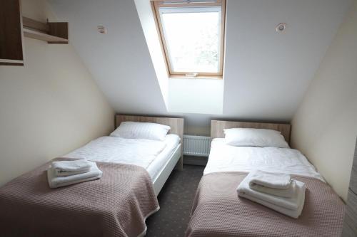 two twin beds in a room with a window at Apartamenty Leśny Zakątek in Dziemiany