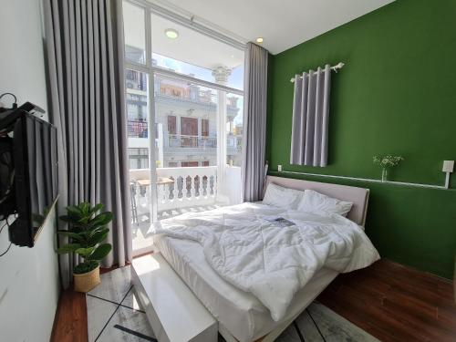 a green bedroom with a bed and a window at B-HOMEAWAY in Ho Chi Minh City
