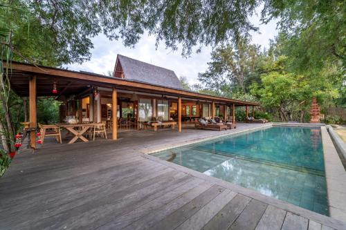 a house with a swimming pool and a wooden deck at Villa Pulau Cinta Boutique Suites in Gili Meno