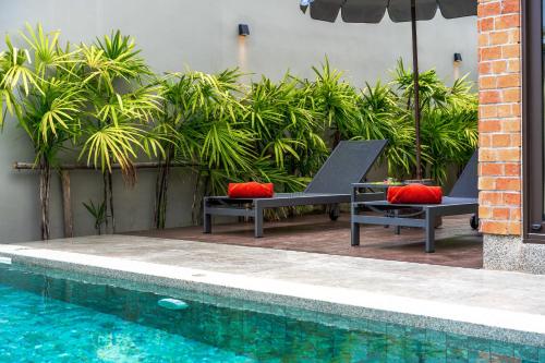 two benches with red pillows next to a swimming pool at Thai Fight Hotel in Lamai