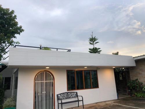 a white house with a bench in front of it at นอนนี่แอทเขาค้อ in Khao Kho