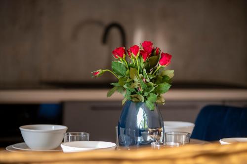 a blue vase with red flowers on a table at Easy Rent Apartments - Kosmos, 24h Check-in in Lublin