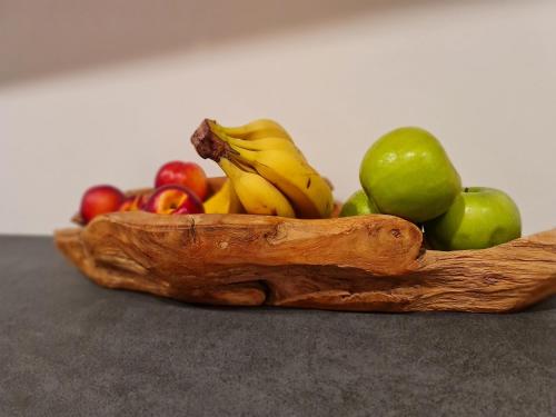 eine Holzschale aus Obst mit Bananen und Äpfeln in der Unterkunft La Culla B&B in Padola