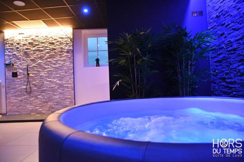 a large tub in a bathroom with a stone wall at Hors du Temps in Aywaille