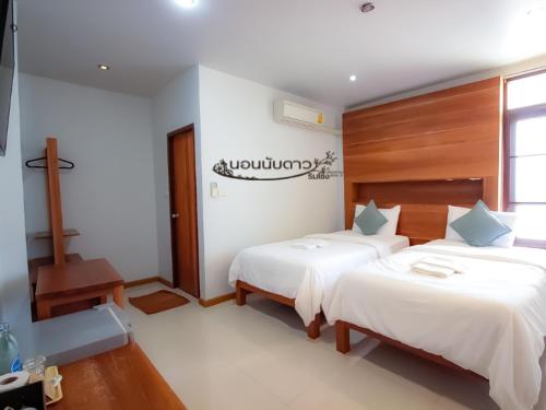 a bedroom with two beds and a sign on the wall at Norn Nab Dao Rimkhong in Chiang Khan