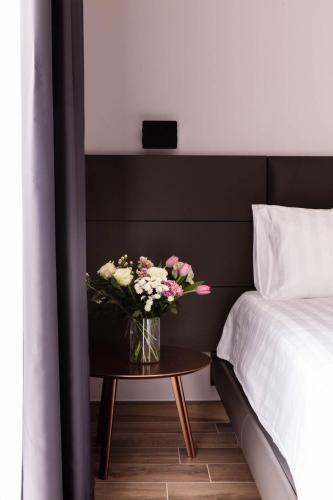 a vase of flowers on a table next to a bed at Agriturismo Maria Vittoria in Custoza