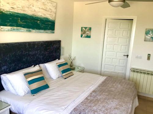 una camera da letto con un letto bianco con cuscini blu e bianchi di La Manga Club Beautiful 2 bedroom Villa with community pool a Cartagena