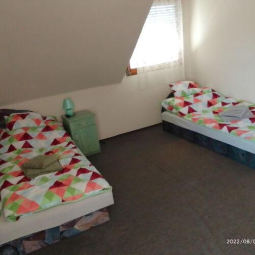 Duas camas num pequeno quarto com uma janela em István Apartman em Tiszafüred