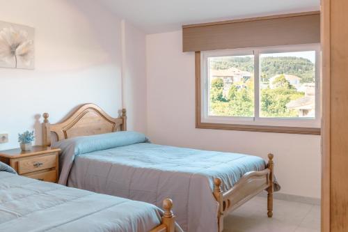 1 dormitorio con 2 camas individuales y ventana en Apartamentos Ambitus Active, en Sanxenxo